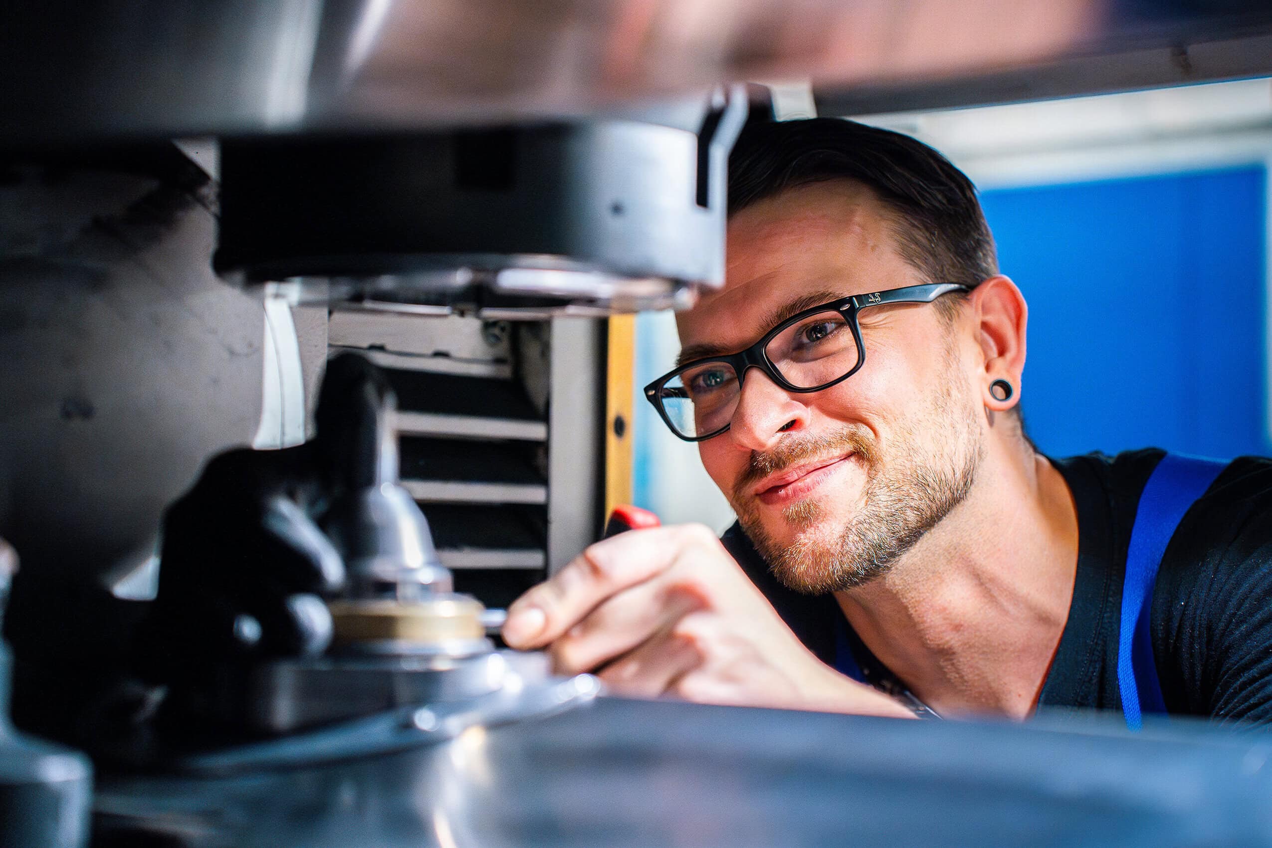 Mitarbeiter Employee of NTN Antriebstechnik GmbH in Gardelegen performing maintenance work on an industrial system with tools and protective equipment in a technical environment.